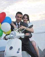 just married couple on the beach ride white scooter photo