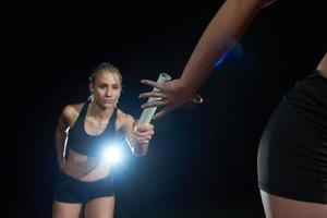 athletic runners passing baton in relay race photo