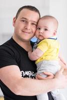 young father holding baby near the window at home photo