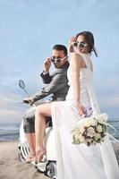 just married couple on the beach ride white scooter photo