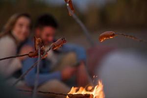 grupo de jóvenes amigos sentados junto al fuego en la playa foto