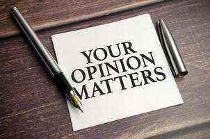 notepad with text YOUR OPINION MATTERS in the wooden background photo