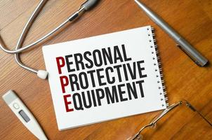 PPE - Personal Protective Equipment is written in a notebook with stethoscope photo