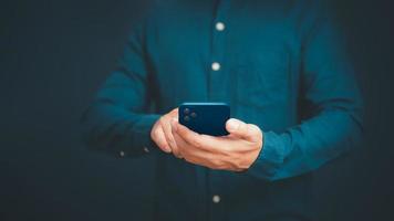 Closeup image of a man holding and using mobile phone or smartphone in room. photo