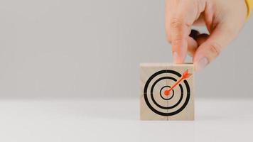 Hand put a goal icon on wooden cubes block on wood table. Business growth and goal in next year concept photo