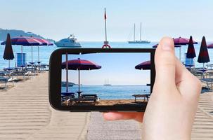 turista tomando fotos de la playa de arena giardini naxos