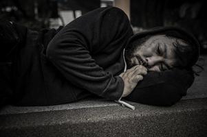 un hombre asiático no tiene hogar en la calle lateral, un extraño tiene que vivir solo en la calle porque no tiene familia. foto