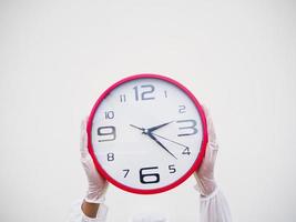 Portrait of doctor or scientist in PPE suite uniform holding red alarm clock In various gestures. COVID-19 concept isolated white background photo