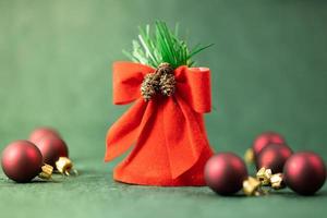 Festive banner, red bell and Christmas tree baubles on a green background photo