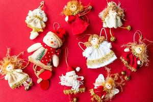 Handmade Christmas decorations. Angels, snowmen, santa. Red background. View from above. photo