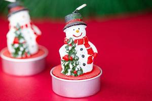 Smiling Christmas snowman with a Christmas tree in his hand. Christmas decoration on a red background. photo