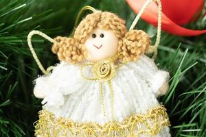 A handmade fabric angel with a background of green Christmas tree branches. A symbol of holiness and special time for people. photo