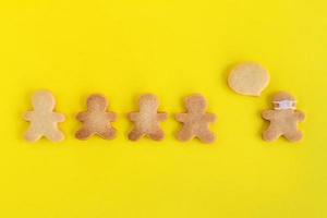 Galletas caseras de pan dulce con glaseado blanco sobre fondo amarillo, vista superior. multitud de personas y un hombre con mascarilla y con nube de llamadas. foto