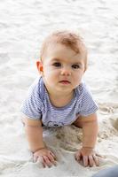 Little baby girl playing with sand at beach. Sensory development for kids outdoors. photo