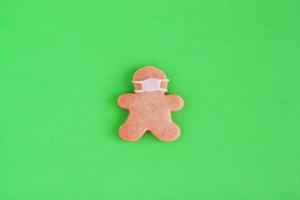 galletas caseras en forma de hombre con máscara médica sobre fondo verde, vista superior. pan dulce con glaseado blanco. foto