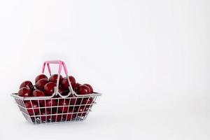 Shopping basket full of sweet berries on white background with copy space. Concept of shopping in supermarket. photo