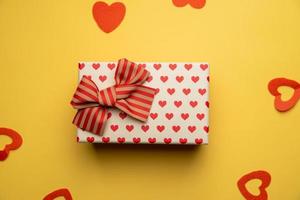 White gift box with red bow on yellow background,flat lay photo