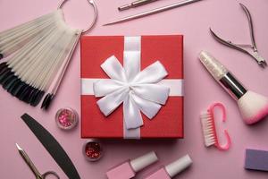 Set of manicure tools and accessories with red gift box on a pink background. Hardware manicure,Flat lay. photo