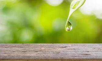 Empty wood table top with rain water drop on green leaf natural blurred background photo