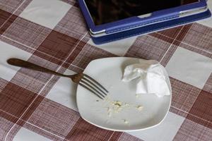 empty white dish with leftovers of eaten food, crumpled table-napkin and steel fork photo