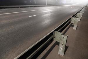 illuminated empty foggy night road with rigid guardrails photo