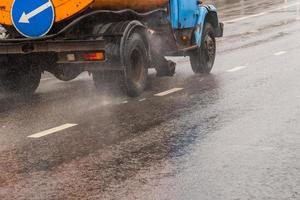 old utility truck moving on asphalt road under rainy day - close-up photo