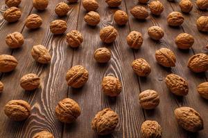 many walnuts with shells evenly spread out on brown wooden surface photo