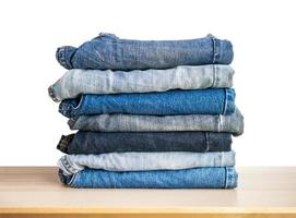 denim blue jeans stack on wood table isolated on white background photo