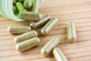 Herbal medicine capsules with bottle on wood table photo