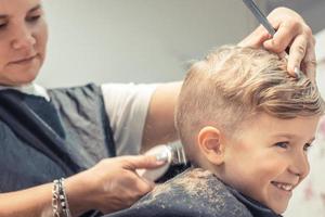 niño feliz cortándose el pelo en la peluquería. foto