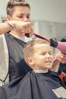 niño secándose el pelo después del corte de pelo en la peluquería. foto