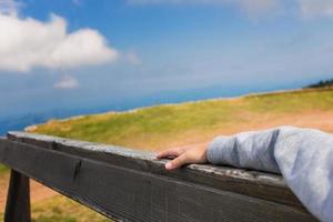Close up of child relaxing on bench at mountain peak. photo