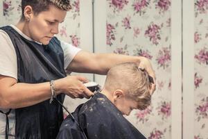 niño pequeño cortándose el pelo por una peluquera. foto