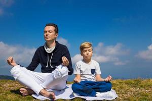 zen como padre e hijo meditando en posición de loto en la cima de la montaña. foto