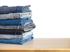 denim blue jeans stack on wood table isolated on white background photo