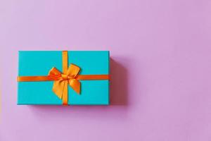 navidad año nuevo cumpleaños san valentín celebración presente concepto romántico. caja de regalo azul de diseño simplemente minimalista aislada sobre fondo violeta violeta. vista superior plana, espacio de copia foto