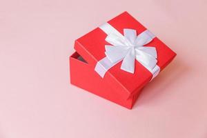 navidad año nuevo cumpleaños san valentín celebración presente concepto romántico. caja de regalo roja de diseño simplemente minimalista aislada sobre fondo de color rosa pastel. vista superior plana, espacio de copia foto