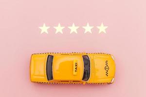 Yellow toy car Taxi Cab and 5 stars rating isolated on pink background. Smartphone application of taxi service for online searching calling and booking cab concept. Taxi symbol. Copy space. photo