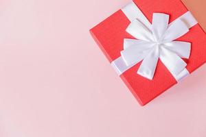 Christmas New Year birthday valentine celebration present romantic concept. Simply minimal design red gift box isolated on pastel pink colorful background. Flat lay top view, copy space photo