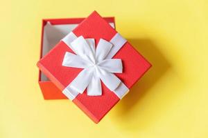 navidad año nuevo cumpleaños san valentín celebración presente concepto romántico. caja de regalo roja de diseño simplemente minimalista aislada sobre fondo amarillo colorido. espacio de copia de vista superior plana. foto