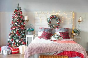 Classic interior room with Christmas tree and traditional white red decorations. Modern clean white classical style interior design apartment bedroom. Christmas eve at home. Minimalist home design. photo