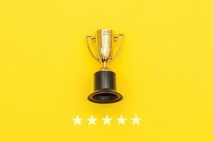 Simply flat lay design winner or champion gold trophy cup and 5 stars rating isolated on pink pastel background. Victory first place of competition. Winning or success concept. Top view copy space. photo