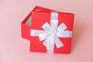 navidad año nuevo cumpleaños san valentín celebración presente concepto romántico. caja de regalo roja de diseño simplemente minimalista aislada sobre fondo de color rosa pastel. vista superior plana, espacio de copia foto