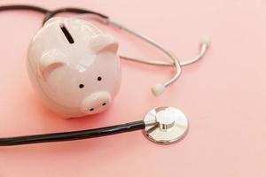 Medicine doctor equipment stethoscope and piggy bank isolated on pink pastel background. Health care financial checkup or saving for medical insurance costs concept. Flat lay top view copy space. photo