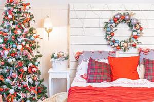 habitación interior clásica con árbol de navidad y decoraciones tradicionales de color rojo blanco. dormitorio de apartamento de diseño de interiores de estilo clásico blanco limpio moderno. Nochebuena en casa. diseño de casa minimalista. foto