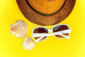 Sunglasses, shell and retro hat on yellow background photo