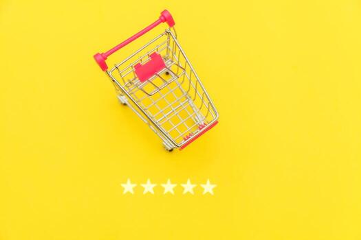 Small supermarket grocery push cart for shopping toy with wheels and 5 stars rating isolated on yellow background. Retail consumer buying online assessment and review concept. photo