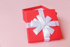 Christmas New Year birthday valentine celebration present romantic concept. Simply minimal design red gift box isolated on pastel pink colorful background. Flat lay top view, copy space photo