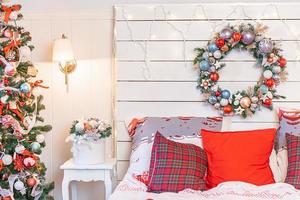 habitación interior clásica con árbol de navidad y decoraciones tradicionales de color rojo blanco. dormitorio de apartamento de diseño de interiores de estilo clásico blanco limpio moderno. Nochebuena en casa. diseño de casa minimalista. foto