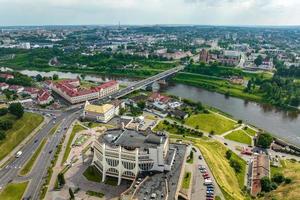 aerial view from great height on red roofs of old city with heavy traffic on bridge with wide multi-lane road across wide river photo